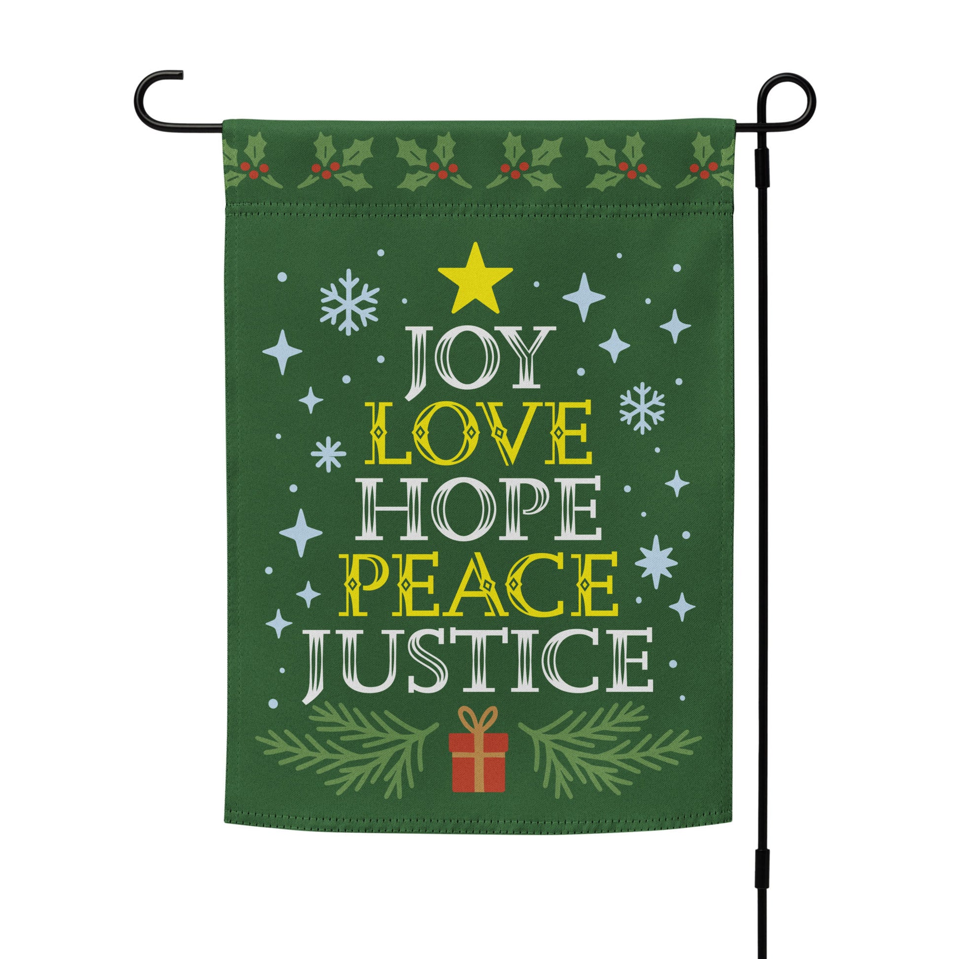 Green garden flag on a metal stand with holiday accents and bold white and yellow text reading “JOY LOVE HOPE PEACE JUSTICE,” framed by stars and greenery.