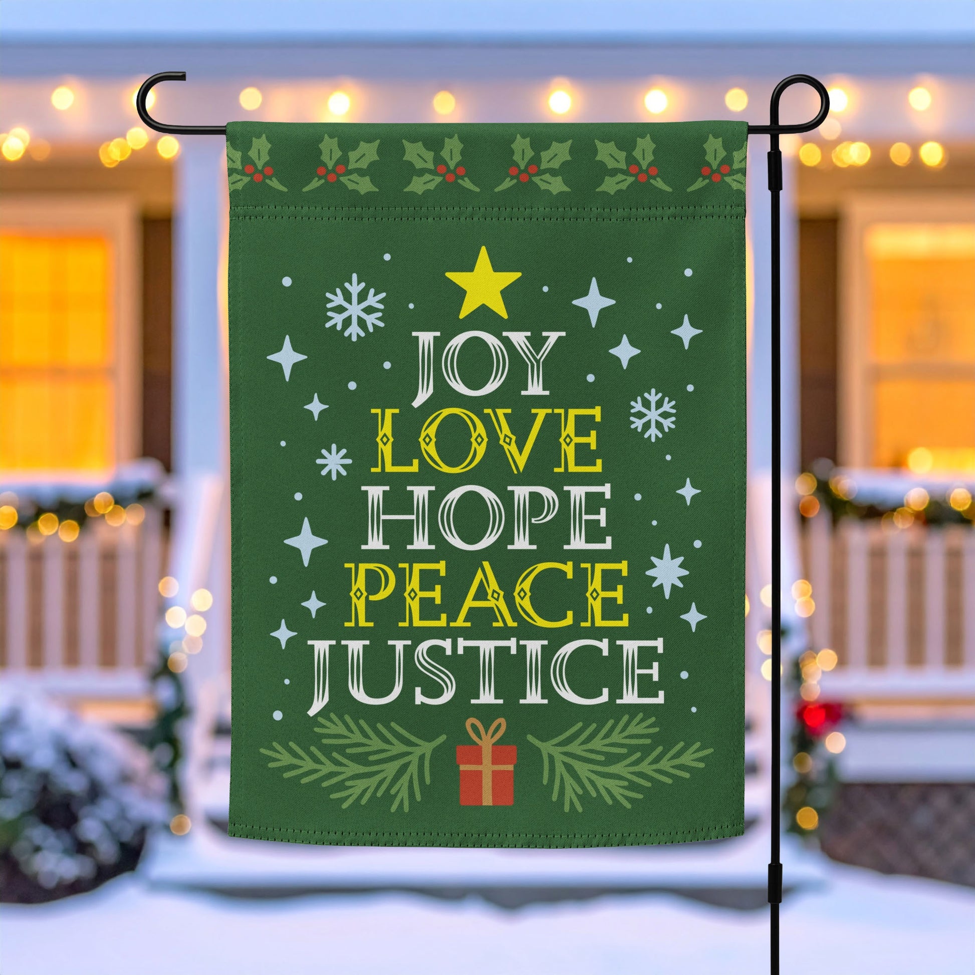 Green garden flag on a metal stand with white and yellow festive lettering reading “JOY LOVE HOPE PEACE JUSTICE,” surrounded by stars, snowflakes, and greenery, outdoor décor by Blue Wave USA.