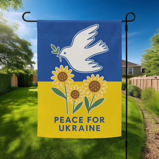 “Peace for Ukraine” garden flag featuring white dove with olive branch and sunflowers on a blue and yellow background, displayed outdoors on a flag stand.