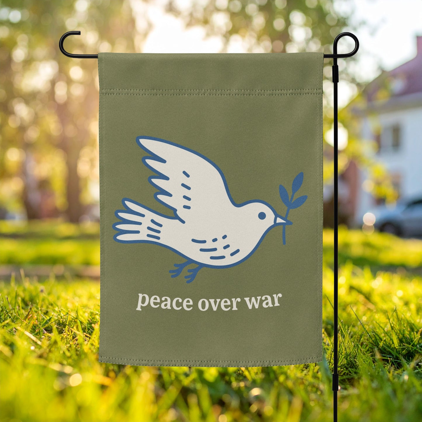 Garden flag featuring white dove carrying an olive branch with “peace over war” text on olive green background, minimalist anti-war outdoor decor.