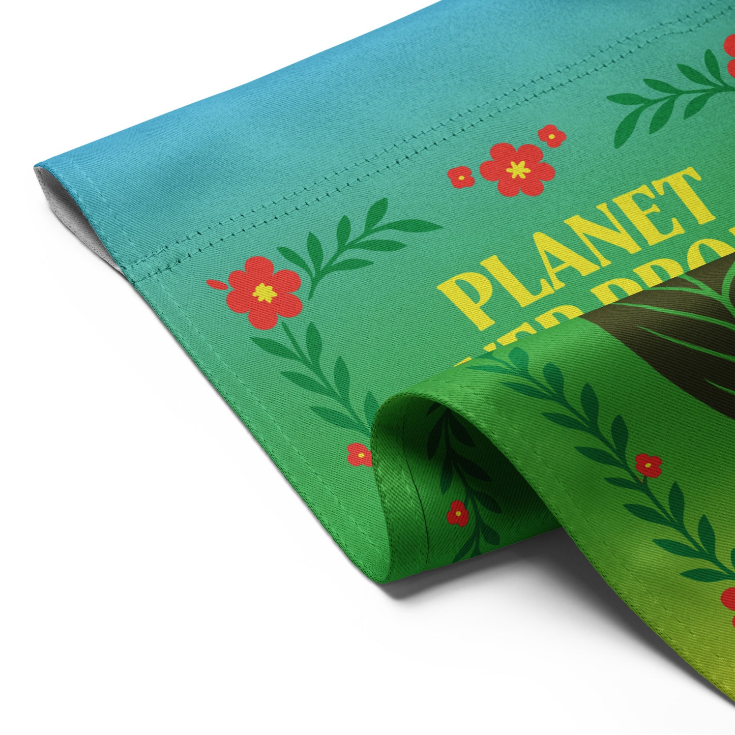 Angled view of the “Planet Over Profit” garden flag showing folded corner with floral border and leaf design.