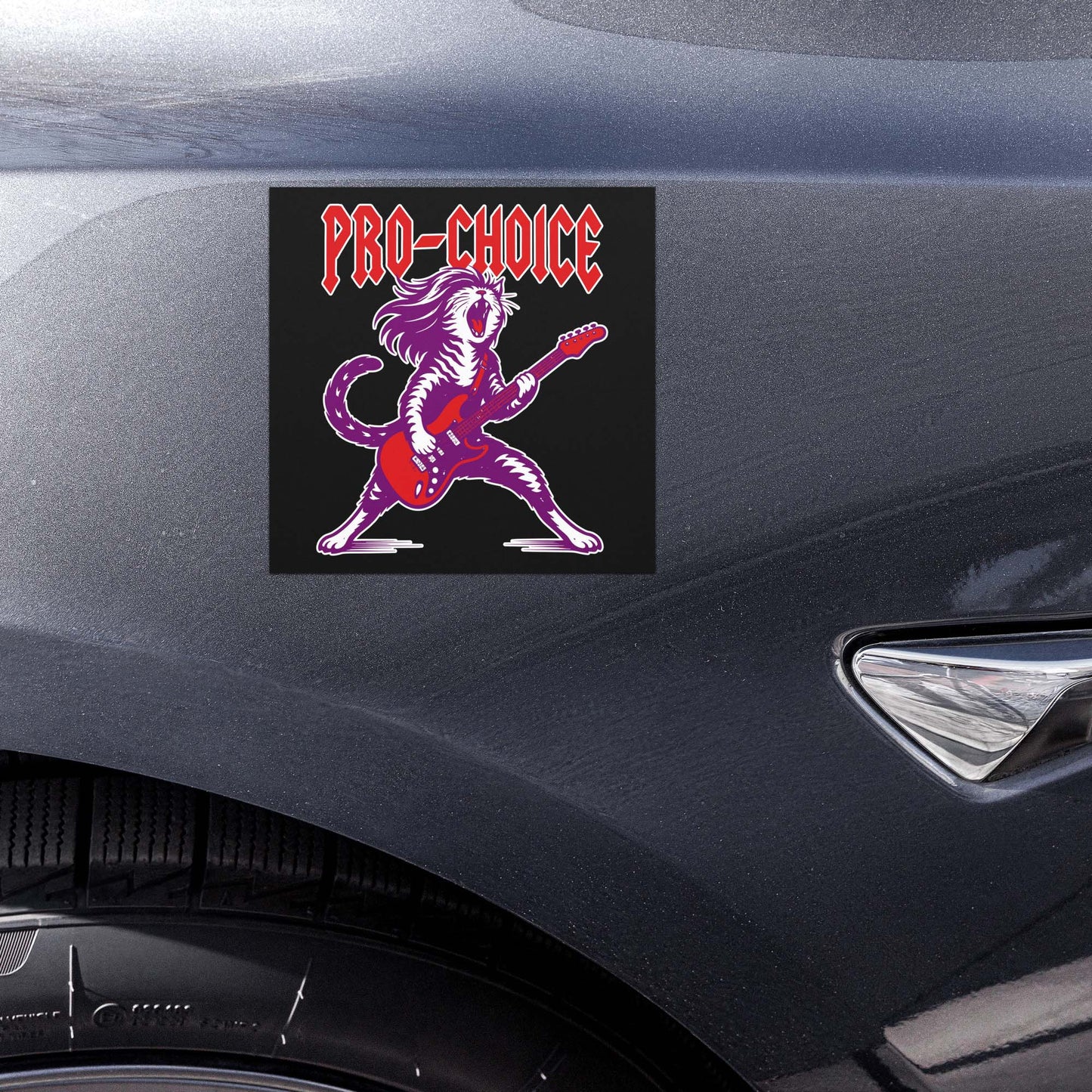 Close-up view of the square black car magnet on a vehicle body panel, highlighting the rockstar cat illustration with electric guitar and bold red “PRO-CHOICE” text.