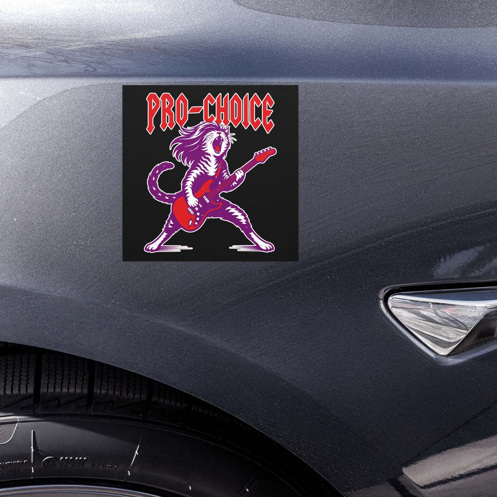 Close-up view of the square black car magnet on a vehicle body panel, highlighting the rockstar cat illustration with electric guitar and bold red “PRO-CHOICE” text.