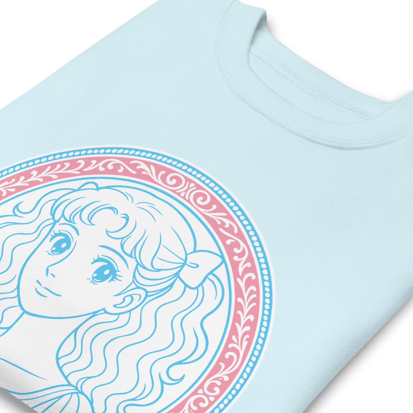 Sky blue unisex premium sweatshirt close-up highlighting pastel blue illustrated portrait, pink circular detailing, and the phrase “Protect The Dolls.”
