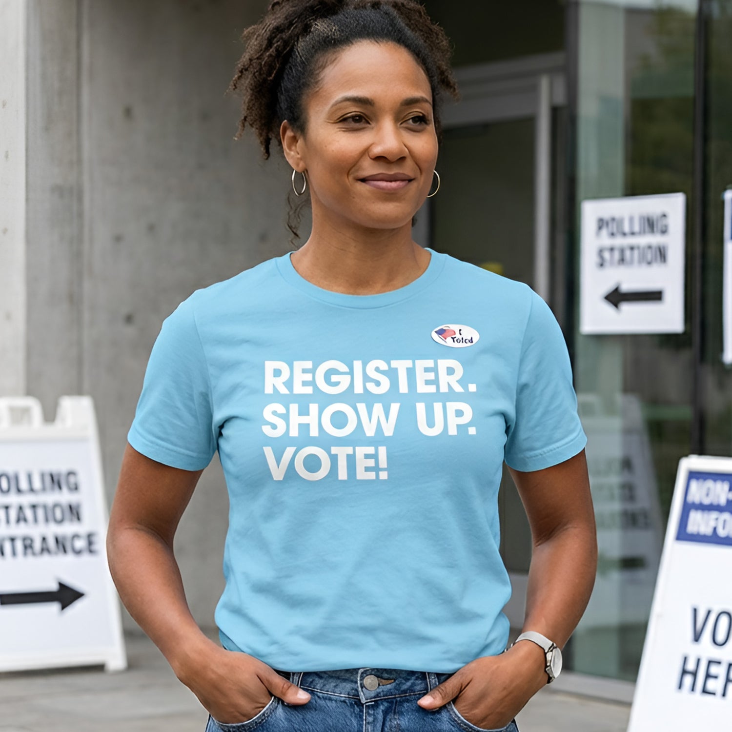 Model wearing light blue unisex classic tee featuring bold white text reading “REGISTER. SHOW UP. VOTE!” standing outside polling station entrance with voting signs visible.