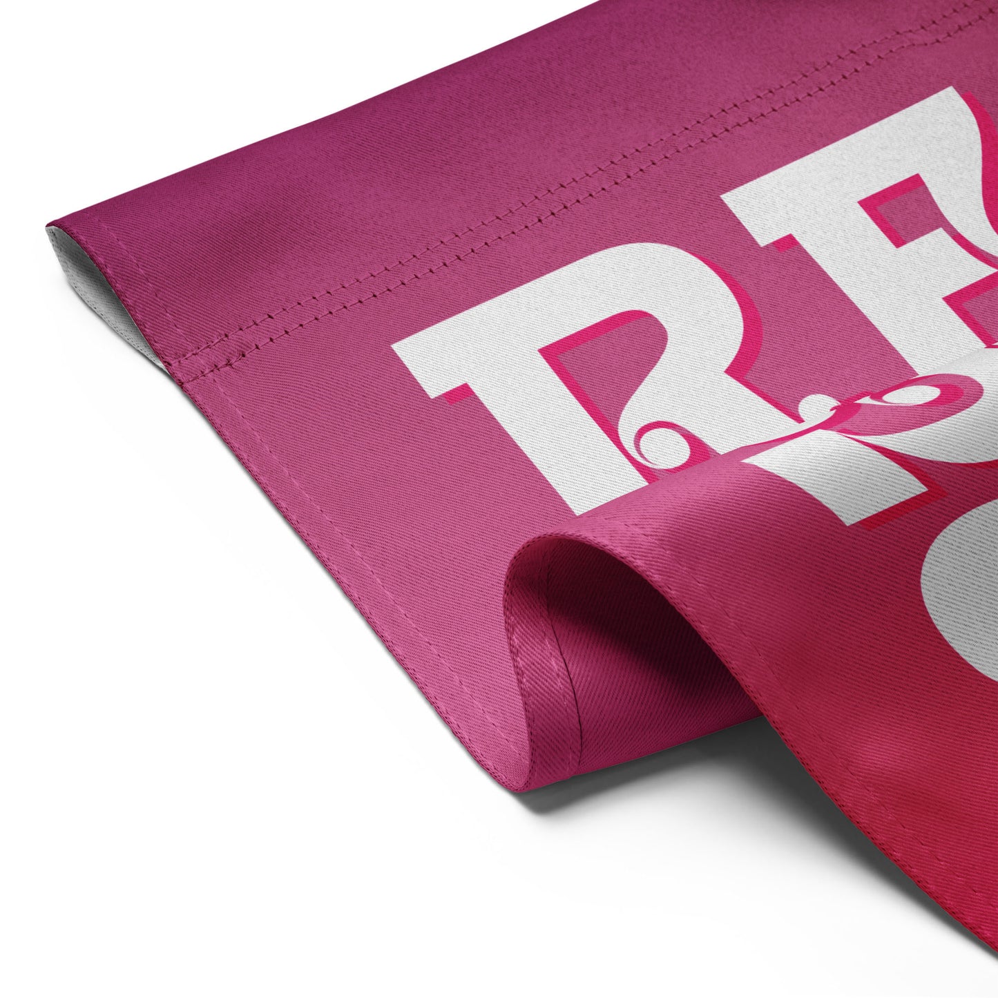 Close-up folded pink garden flag detail showing bold white “RE” typography and fabric texture from the retro protest design.