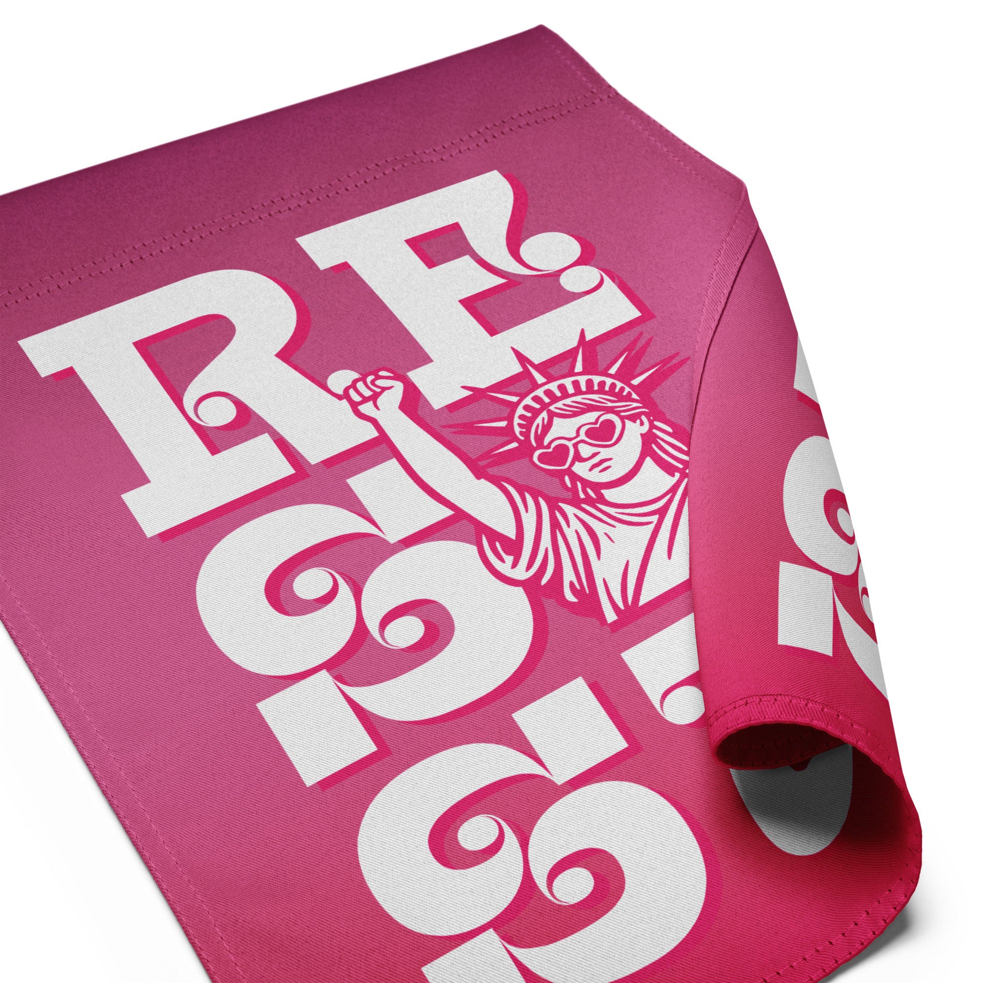 Folded pink garden flag featuring partial “RESIST” lettering with visible Statue of Liberty artwork, bold activist outdoor decor in retro feminist style.