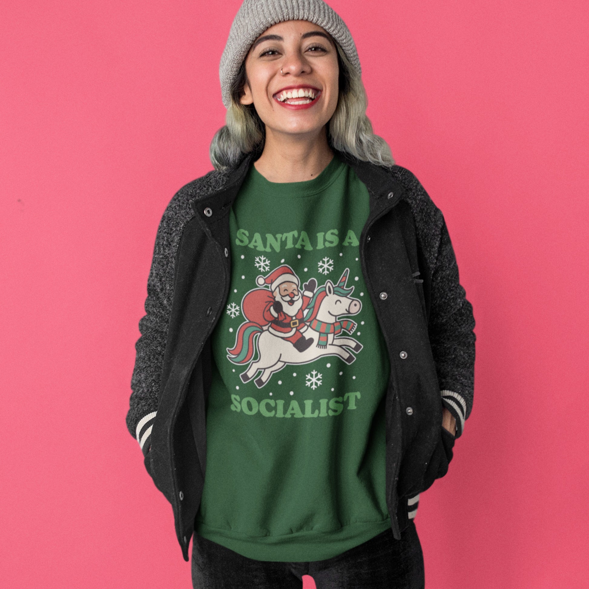 Model smiling while wearing a green sweatshirt with a vintage Santa riding a unicorn illustration, surrounded by stars, and the printed message “SANTA IS A SOCIALIST,” from Blue Wave USA.