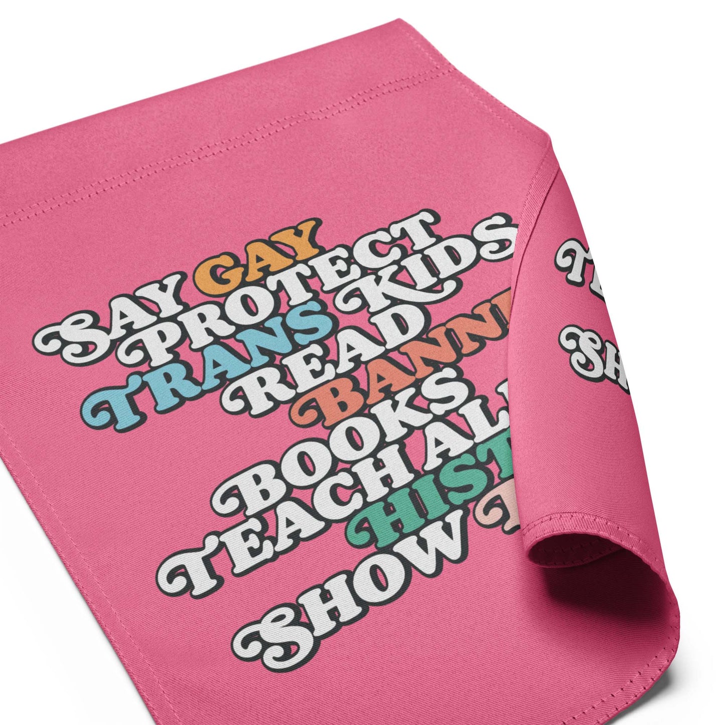 Pink garden flag fabric close-up showing retro stacked typography reading “Say Gay Protect Trans Kids Read Banned Books Teach All History Show Love.”