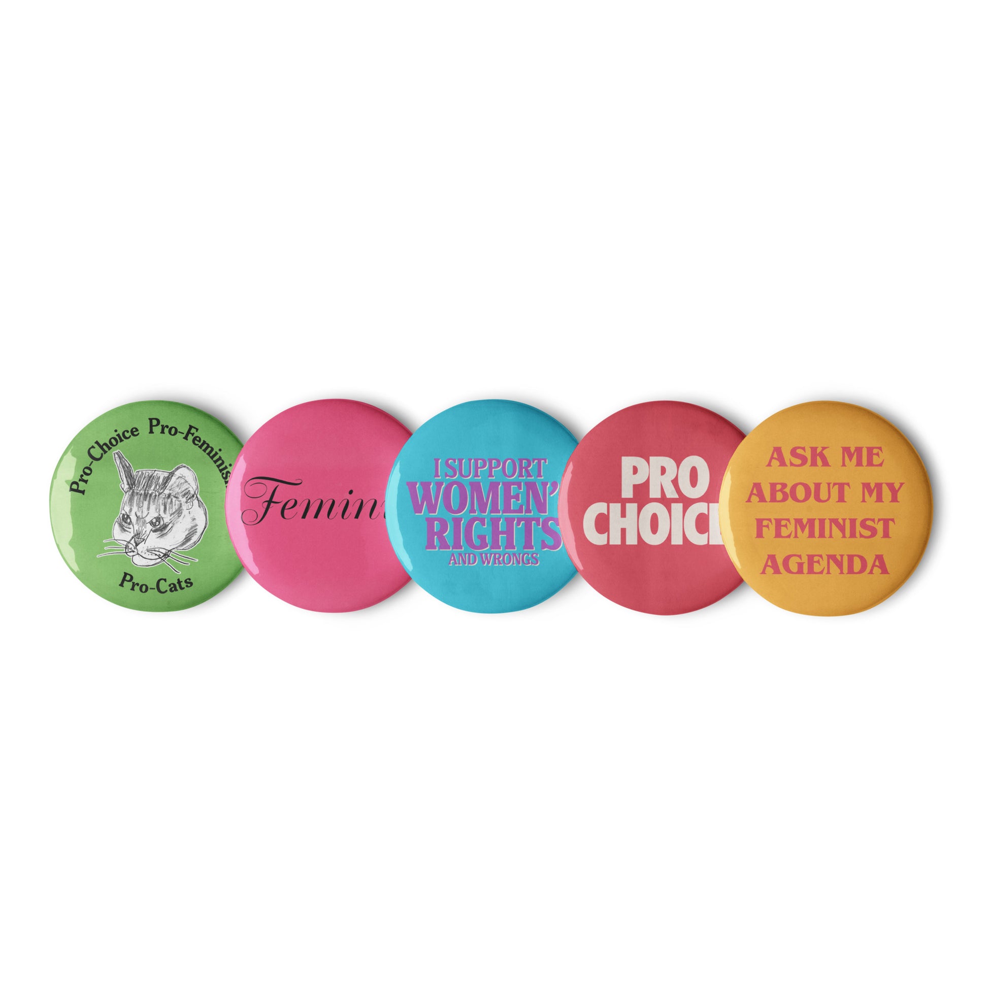 Row of five pastel feminist pin buttons in pink, teal, yellow, and green featuring bold pro-choice and women’s rights messages. Progressive statement pins by Blue Wave USA.