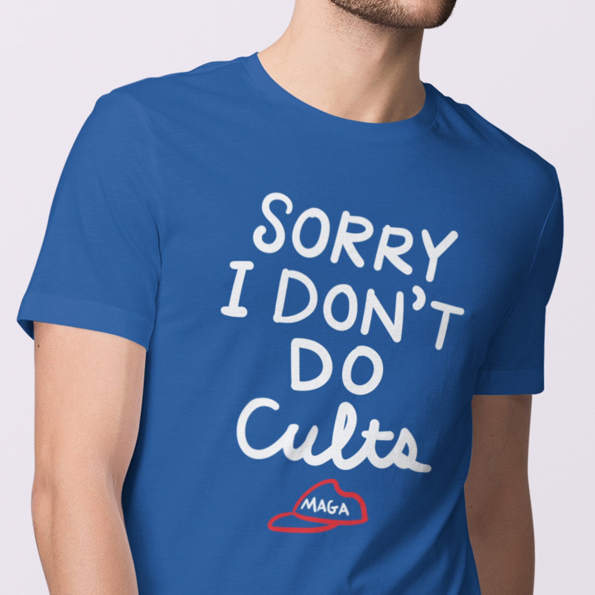 Model wearing blue unisex t-shirt displaying the phrase “SORRY I DON’T DO CULTS.” with crossed-out MAGA hat illustration.