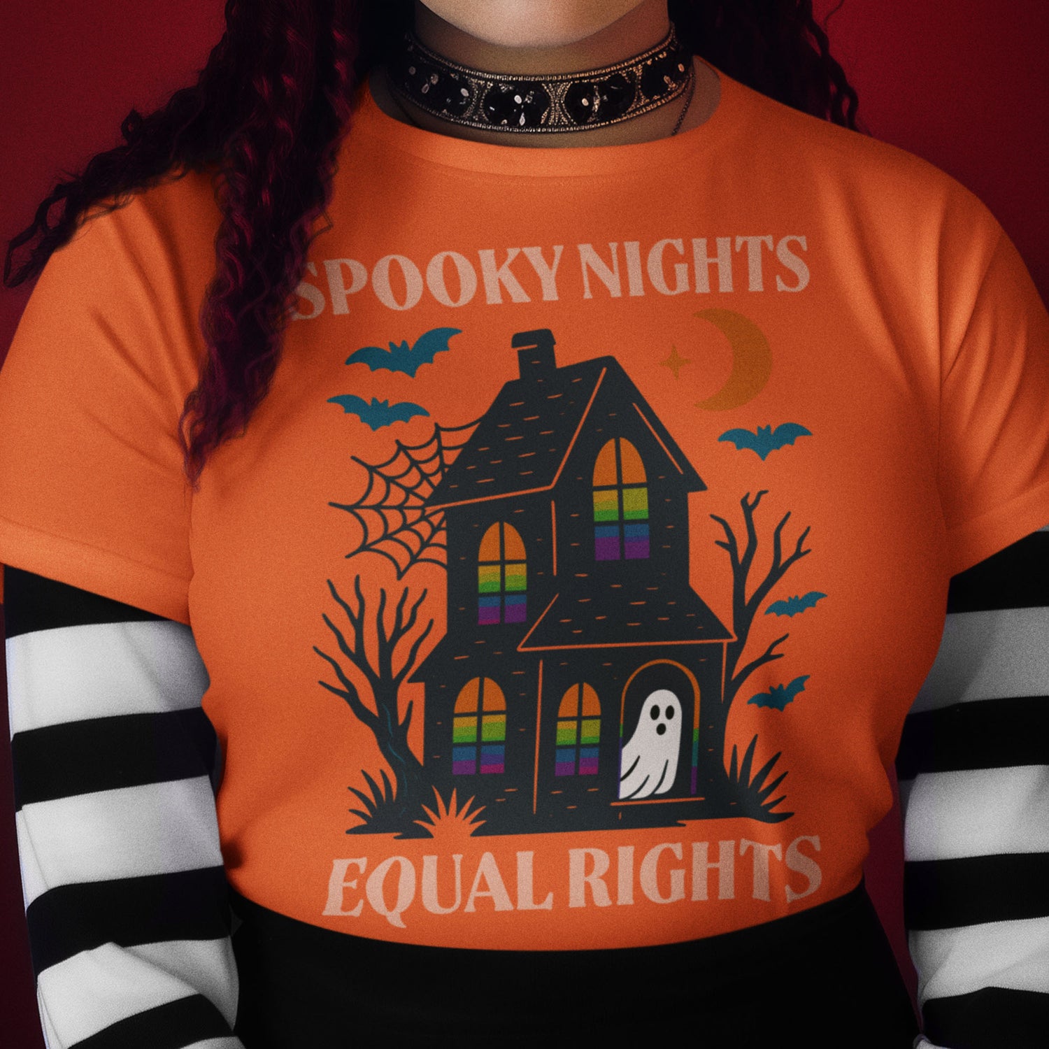 Model wearing orange “Spooky Nights Equal Rights” Halloween activist t-shirt styled with striped sleeves.