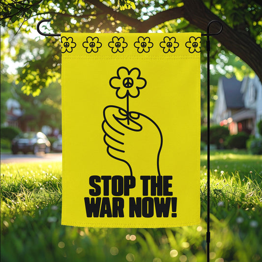 Garden flag featuring black line-art hand holding flower with bold “STOP THE WAR NOW!” message on bright yellow background displayed on lawn stake.