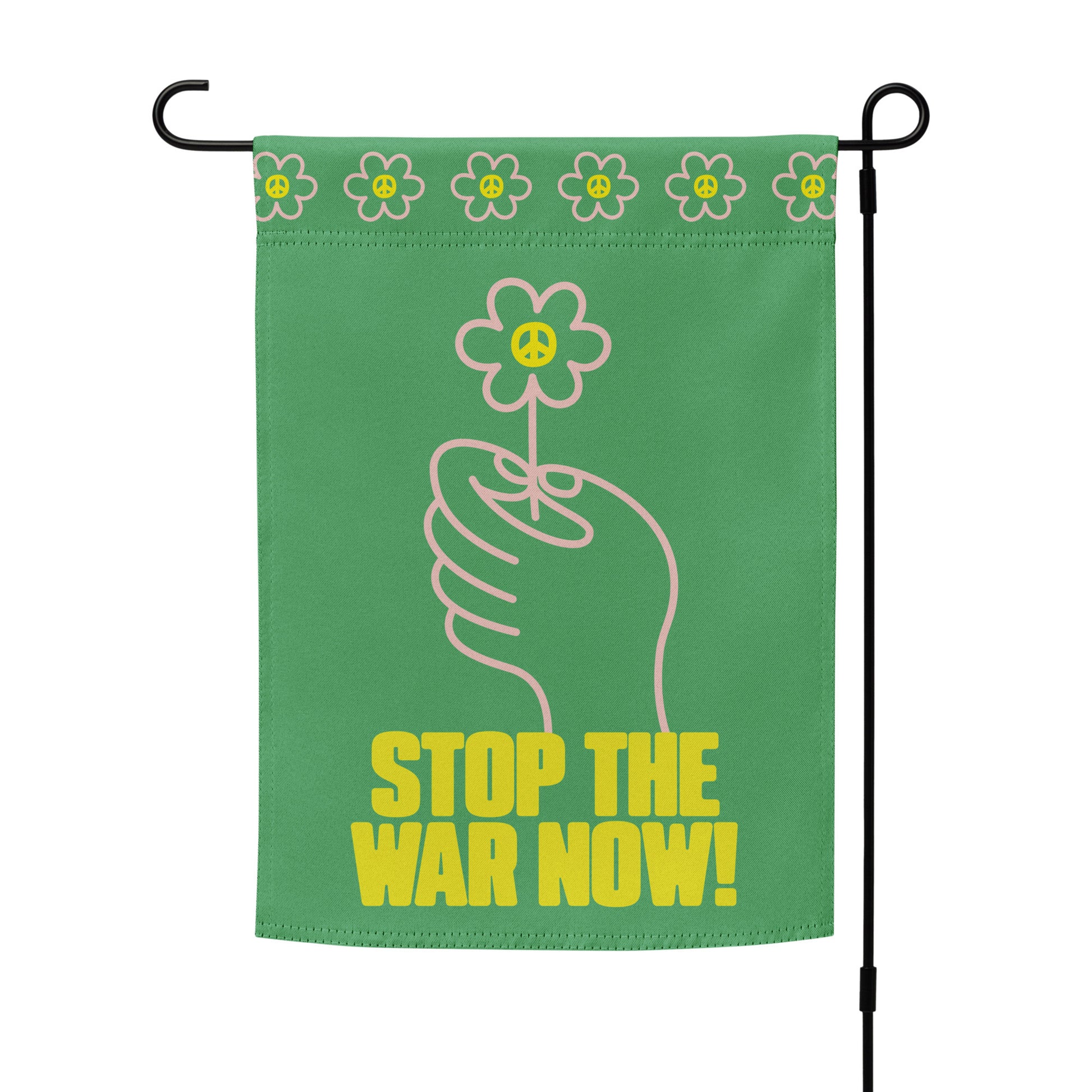 Green garden flag mounted on black stand displaying centered hand-and-flower artwork with strong anti-war statement across lower panel.