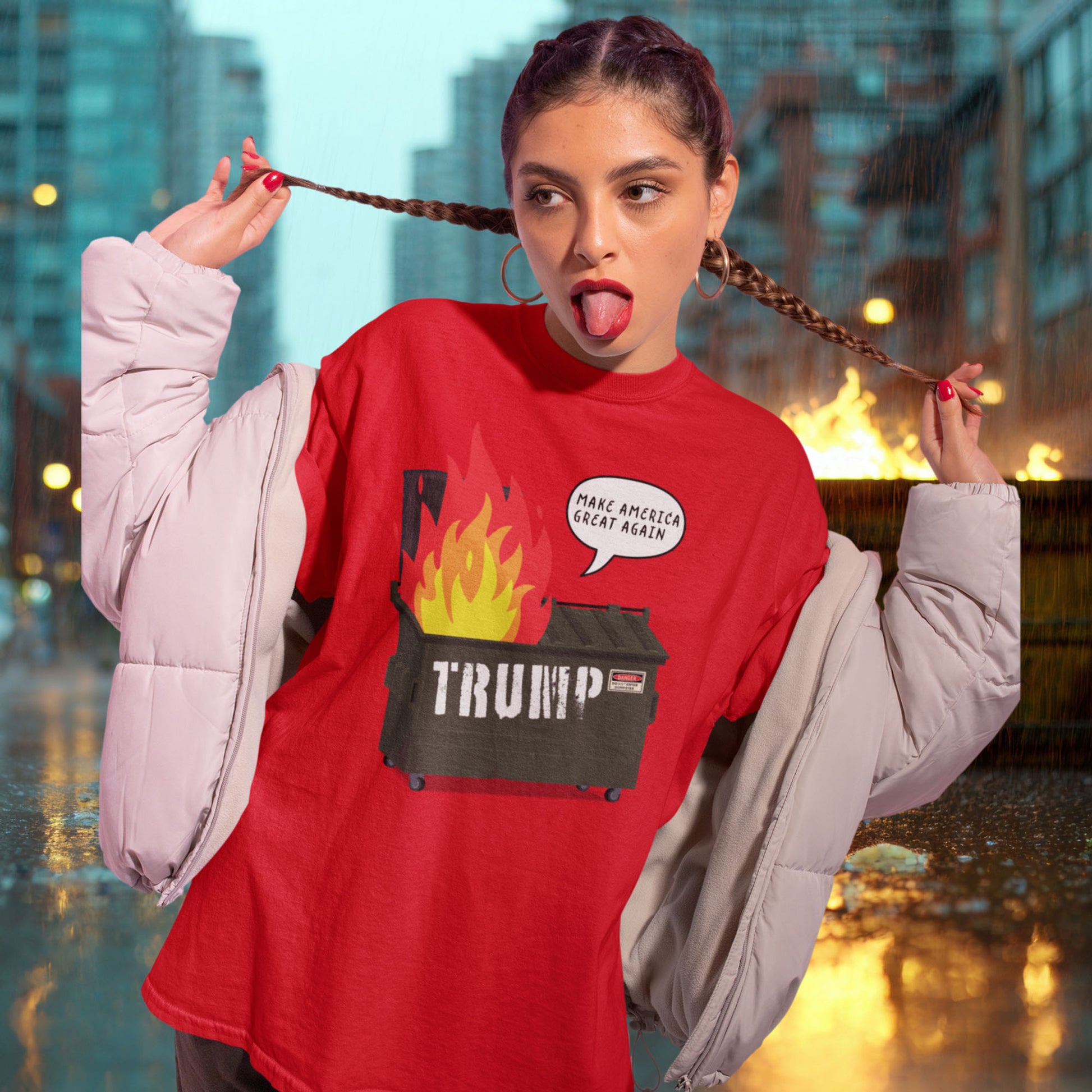 Model wearing red unisex t-shirt featuring flaming dumpster graphic labeled “TRUMP” with speech bubble reading “Make America Great Again,” satirical anti-MAGA protest design.