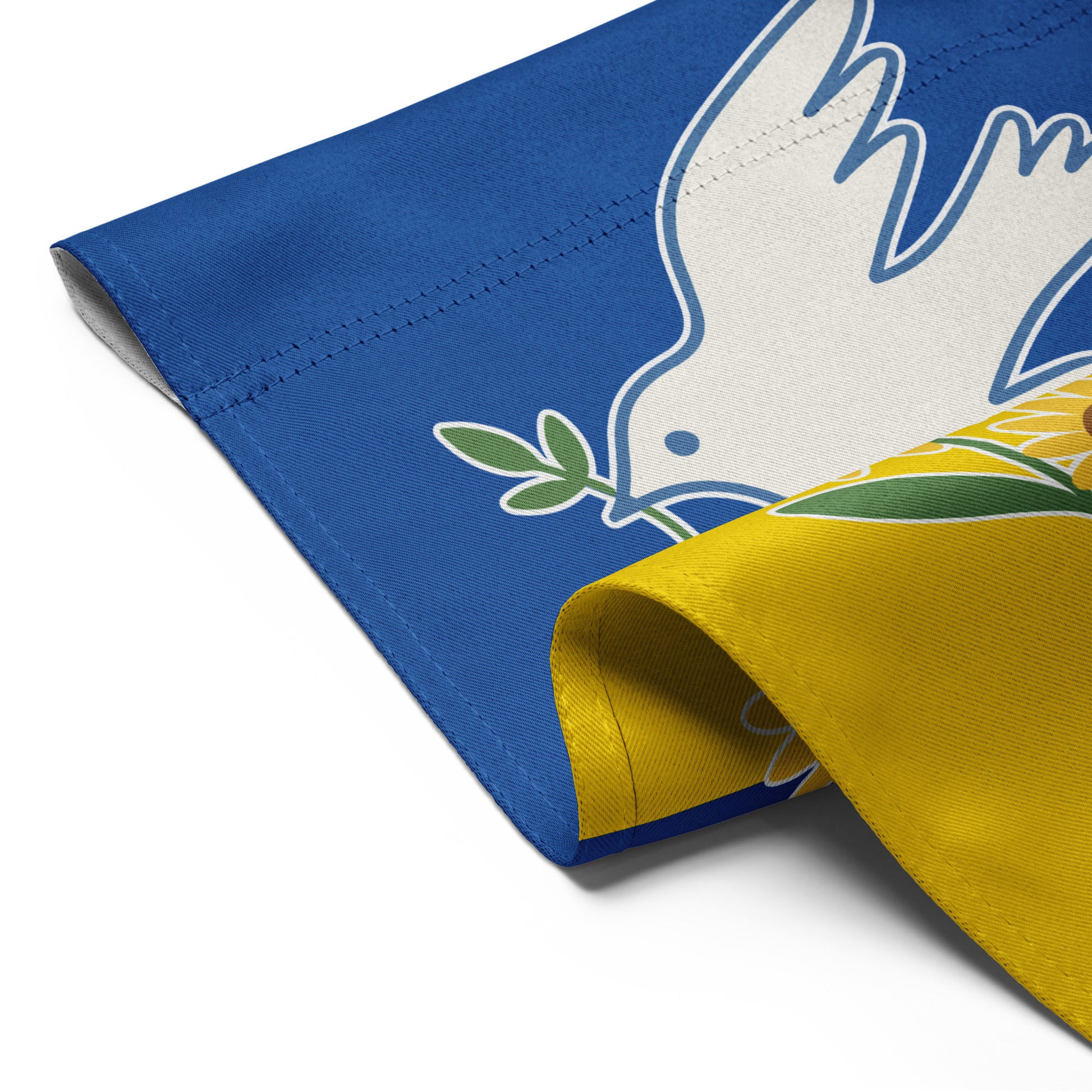 Detailed corner view of the “Peace for Ukraine” garden flag showing stitched edge and part of dove and sunflower artwork.