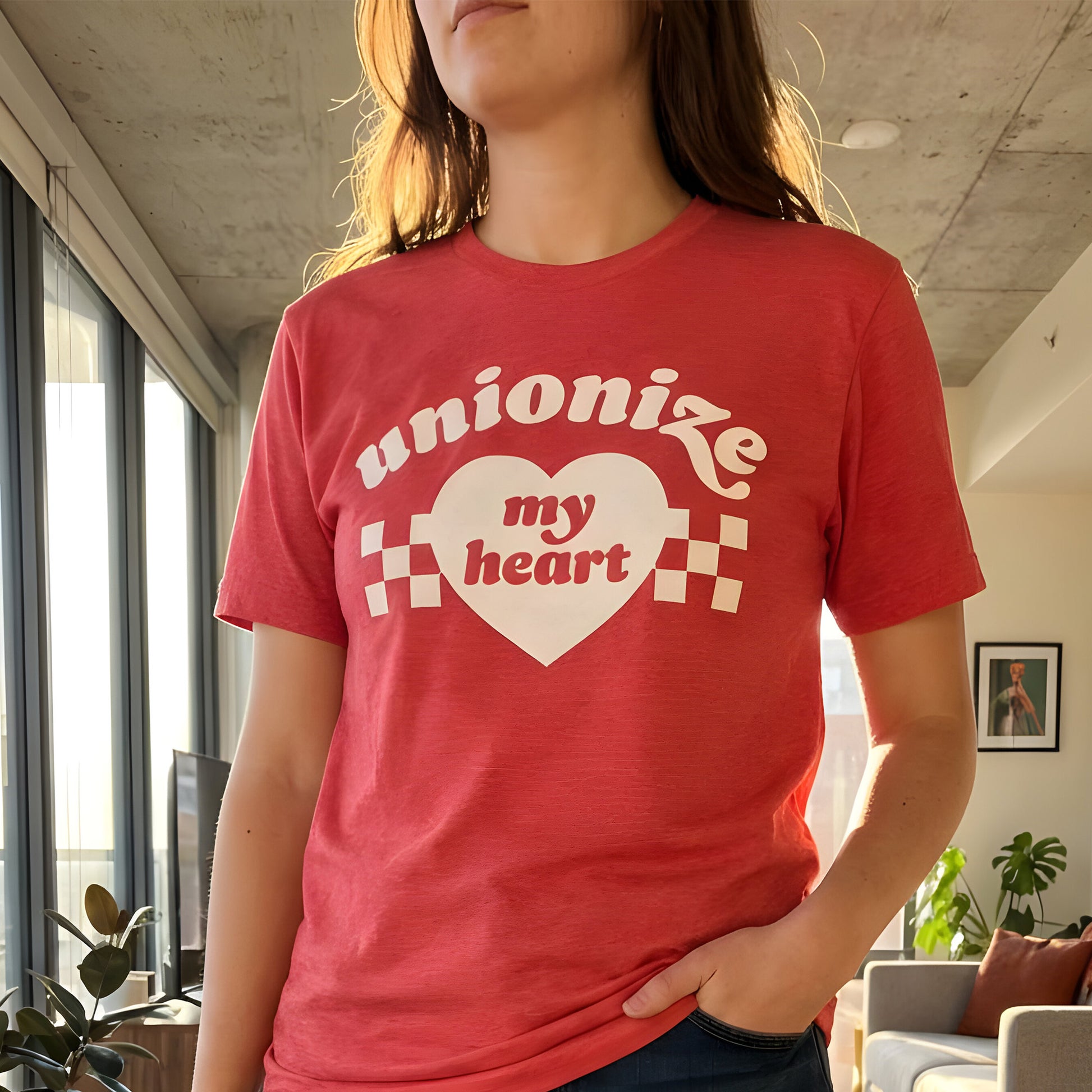 Heather red unisex t-shirt worn by model indoors, featuring bold heart artwork and the phrase “Unionize My Heart,” styled casually for everyday wear with progressive labor-rights message.