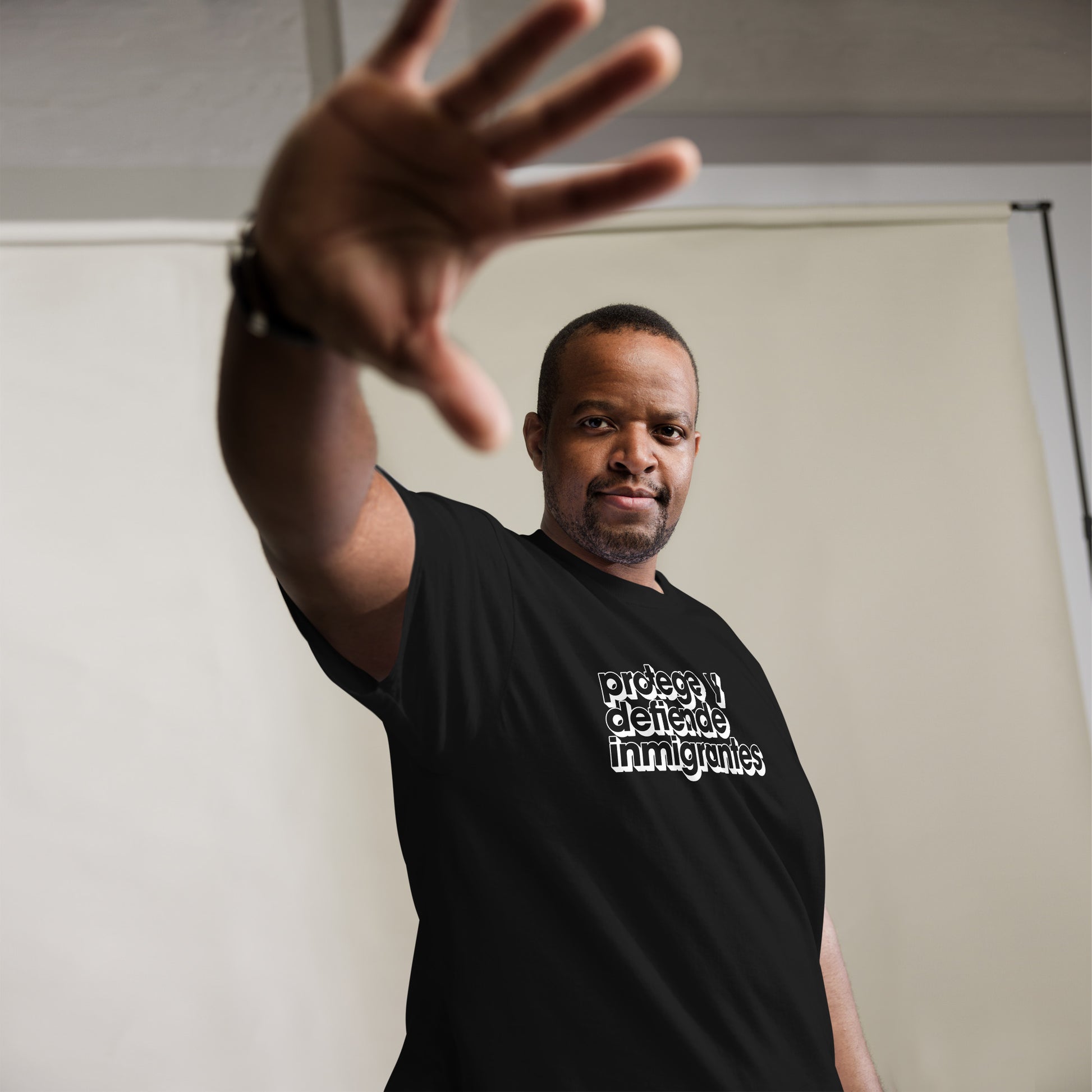 Lifestyle Image: Black Model wearing Protege y Defiende Inmigrantes pro-migrant rights unisex shirt