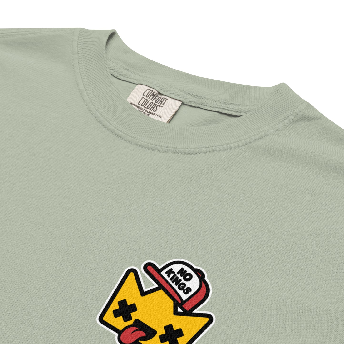 Close-up detail of the “No Kings” cartoon crown graphic printed on a sage green Comfort Colors t-shirt, highlighting the bold artwork and vibrant colors.