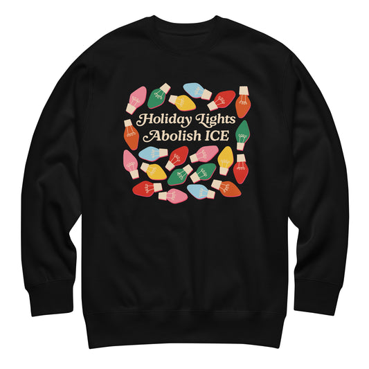 A black unisex sweatshirt featuring colorful holiday bulbs surrounding the message “Holiday Lights Abolish ICE,” displayed flat to highlight its bold progressive holiday design.