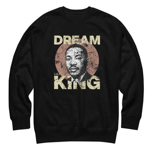 Black unisex premium sweatshirt featuring the distressed “DREAM LIKE KING” text with MLK’s portrait inside a textured circle. Vintage civil-rights inspired design from Blue Wave USA.