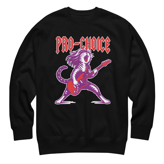 Black unisex premium sweatshirt featuring a bold illustrated cat playing electric guitar in a heavy metal style, red lettering reading “PRO-CHOICE,” vibrant purple and pink graphic.