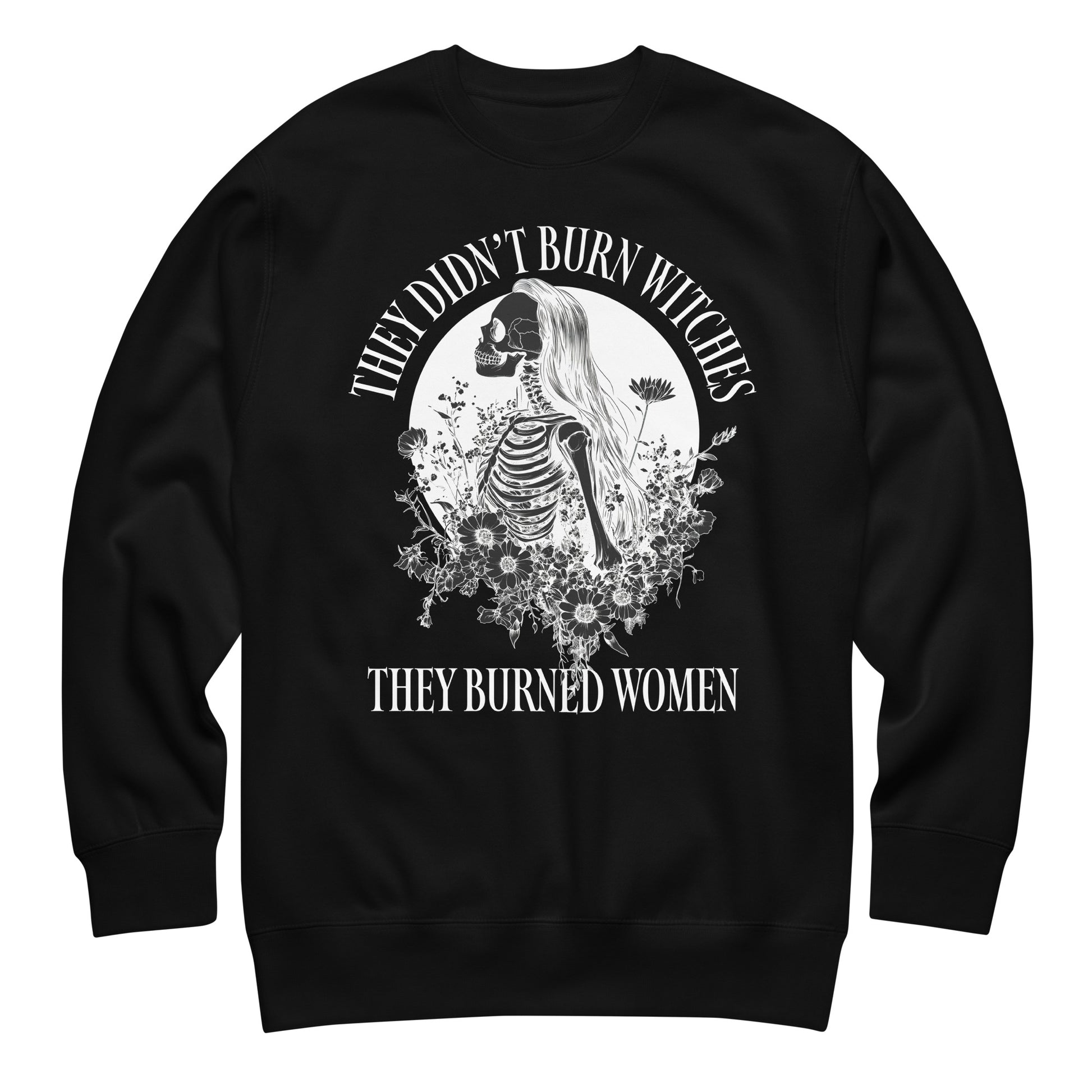 Unisex premium sweatshirt featuring detailed gothic illustration of skeletal woman framed by floral and celestial motifs, high-contrast white artwork, printed message “THEY DIDN’T BURN WITCHES THEY BURNED WOMEN,” black fabric.