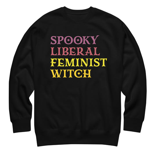 Unisex premium sweatshirt featuring stacked retro block typography in pink, yellow, and purple tones, bold centered layout, printed message “SPOOKY LIBERAL FEMINIST WITCH,” black fabric.
