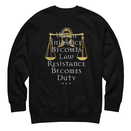 Black unisex premium sweatshirt featuring Lady Justice scales illustration with serif typography reading “WHEN INJUSTICE BECOMES LAW RESISTANCE BECOMES DUTY,” centered gold graphic.