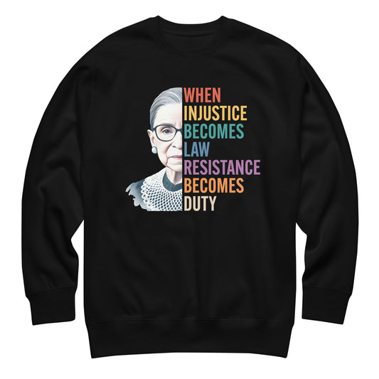 Black unisex premium sweatshirt featuring Ruth Bader Ginsburg portrait with rainbow typography reading “WHEN INJUSTICE BECOMES LAW RESISTANCE BECOMES DUTY,” centered progressive graphic.