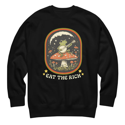 Black unisex premium sweatshirt featuring frog playing banjo on mushroom with stars and bold “Eat The Rich” anti-capitalist protest design from Blue Wave USA.