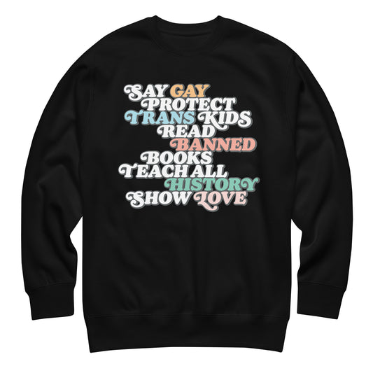 Black unisex premium sweatshirt featuring retro stacked typography reading “Say Gay Protect Trans Kids Read Banned Books Teach All History Show Love,” progressive apparel from Blue Wave USA.