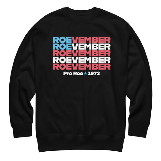 Black unisex premium sweatshirt featuring stacked typography reading “Roevember Pro Roe 1973” in red, white, and blue reproductive rights apparel from Blue Wave USA.