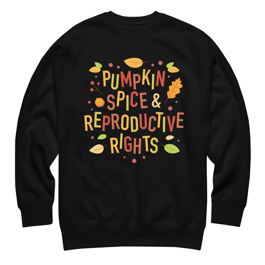 Black unisex premium sweatshirt featuring illustrated fall typography reading “Pumpkin Spice & Reproductive Rights” with autumn leaves and seasonal pro-choice activist graphics from Blue Wave USA.