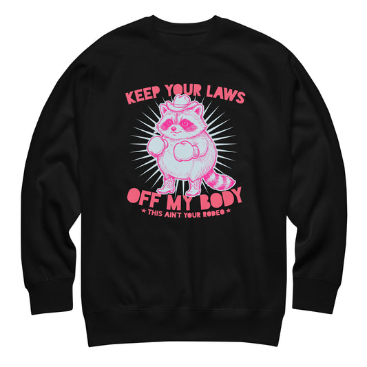 Black unisex premium sweatshirt featuring pink cowboy raccoon with “Keep Your Laws Off My Body” text, bold feminist protest graphic for reproductive rights apparel.
