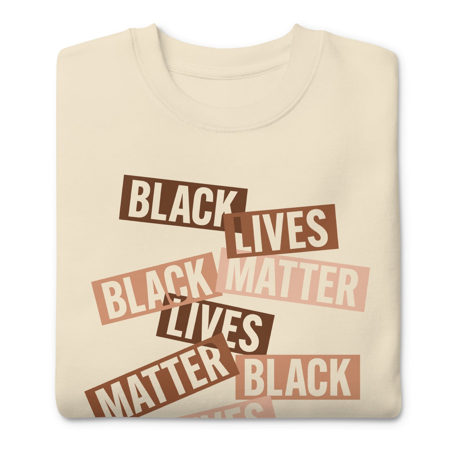 Cream sweatshirt printed with scattered brown word strips reading “BLACK LIVES MATTER.” Soft tones and layered typography create a warm activist aesthetic.