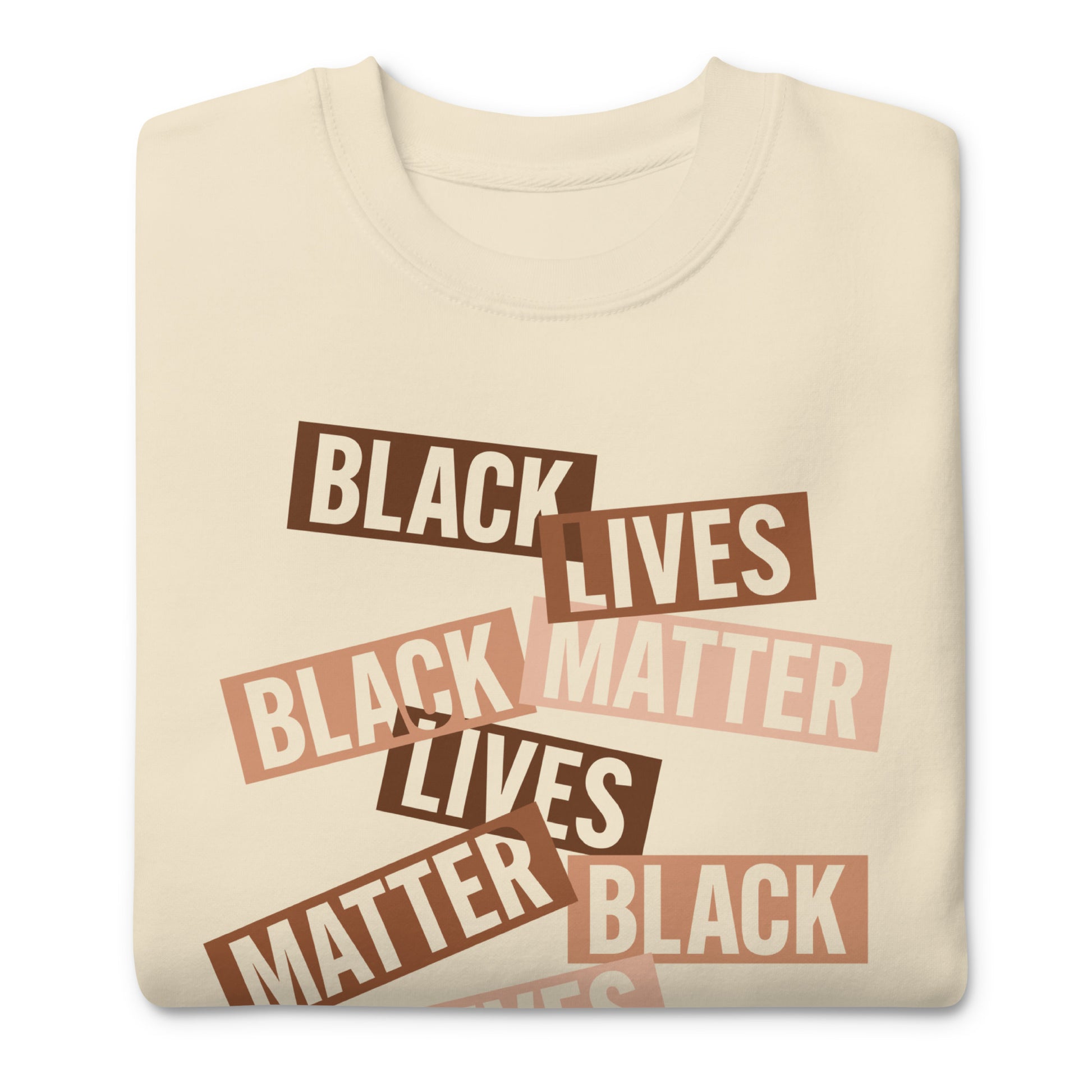 Cream sweatshirt printed with scattered brown word strips reading “BLACK LIVES MATTER.” Soft tones and layered typography create a warm activist aesthetic.