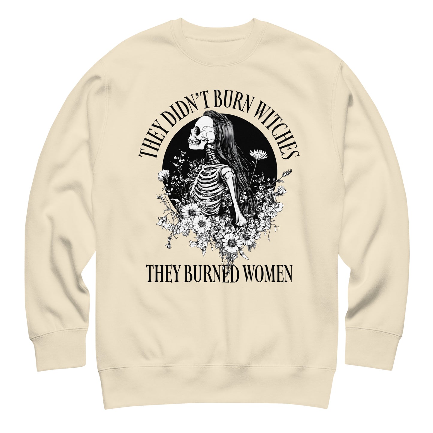 Cream unisex premium sweatshirt laid flat showing ornate skeleton illustration with floral details, high-contrast black print, printed message “THEY DIDN’T BURN WITCHES THEY BURNED WOMEN,” progressive apparel from Blue Wave USA.