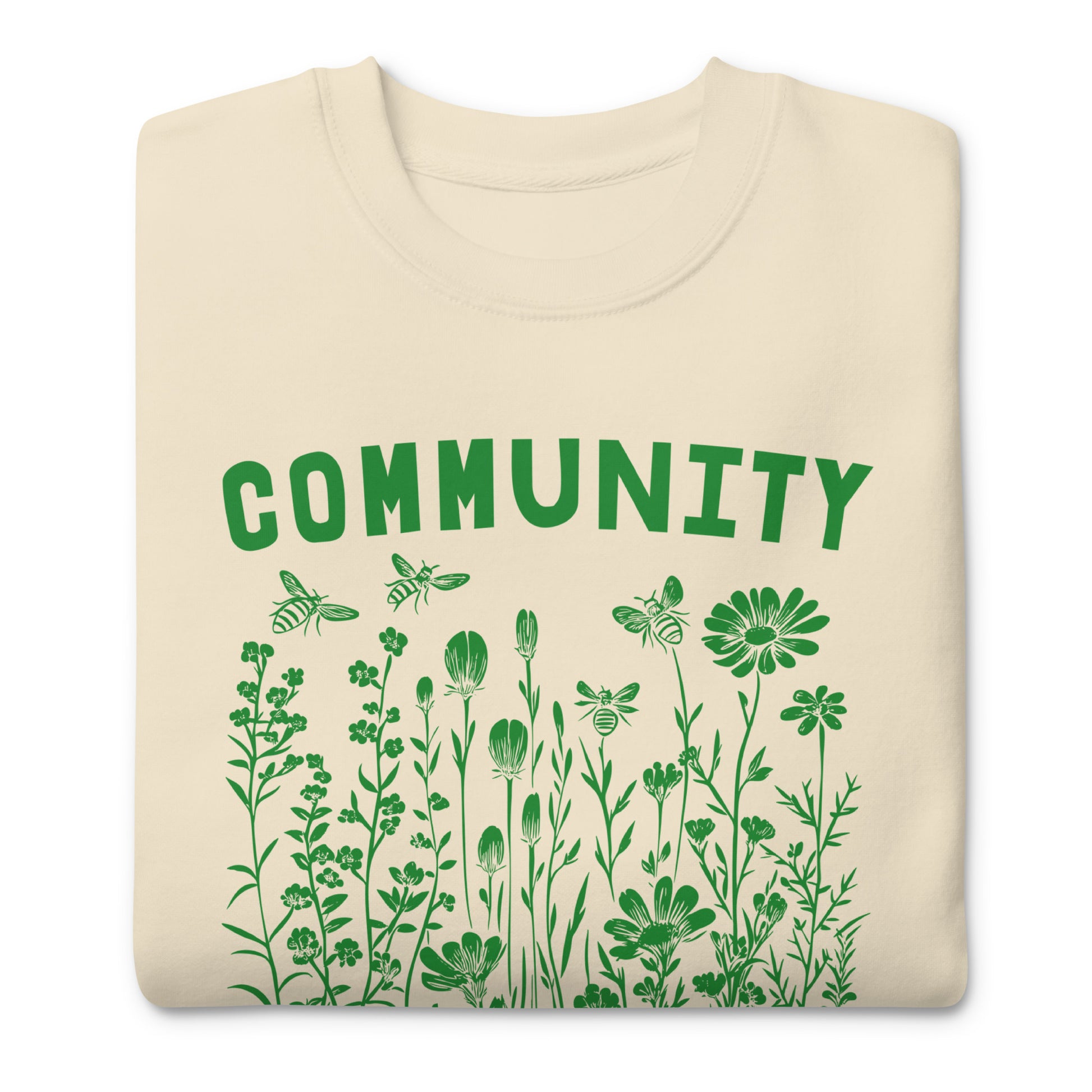 Folded cream unisex premium sweatshirt showing wildflower illustration and botanical typography, centered progressive activist graphic.