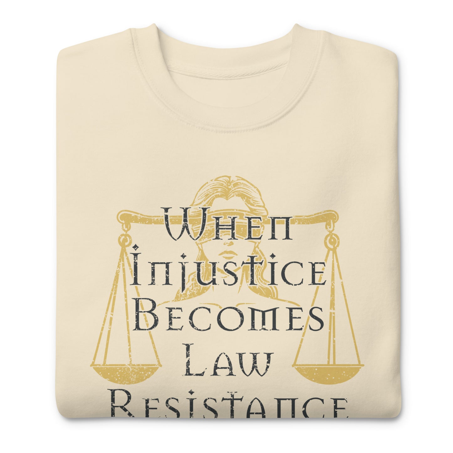 Folded cream unisex premium sweatshirt featuring Lady Justice scales illustration with gold typography, centered social justice graphic.