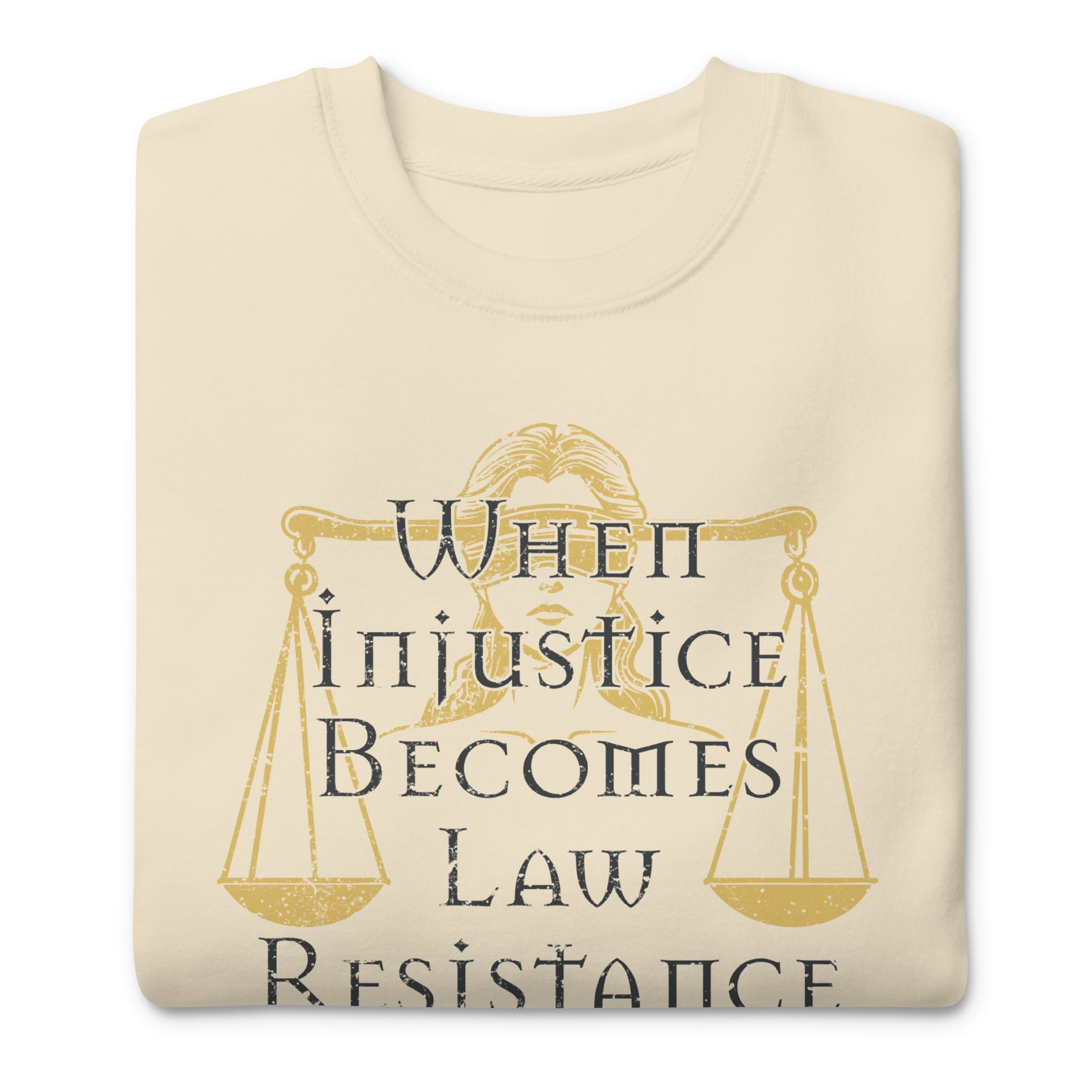 Folded cream unisex premium sweatshirt featuring Lady Justice scales illustration with gold typography, centered social justice graphic.