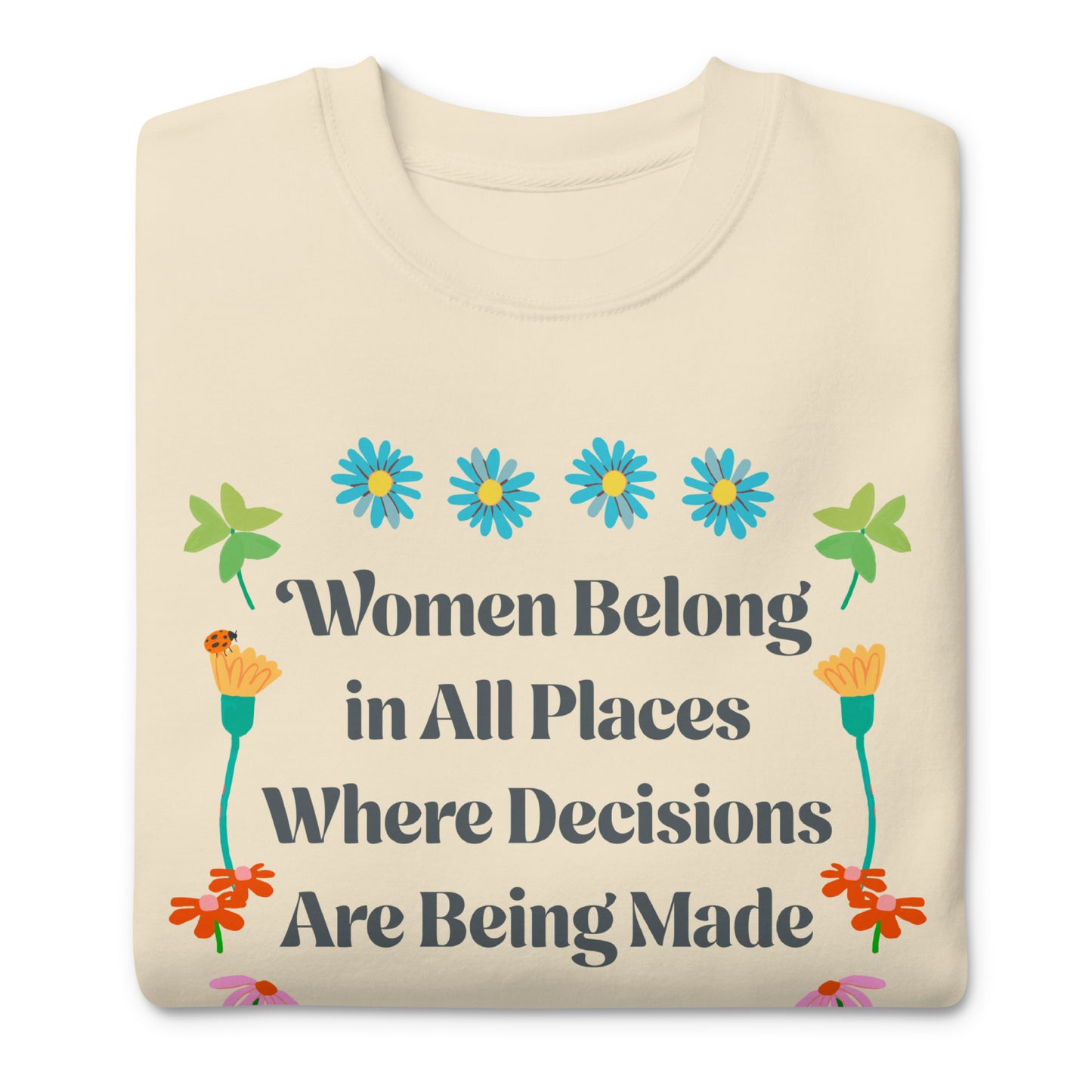 Folded cream sweatshirt displaying Ruth Bader Ginsburg feminist quote with colorful flower illustrations and “Women Belong in All Places” typography.