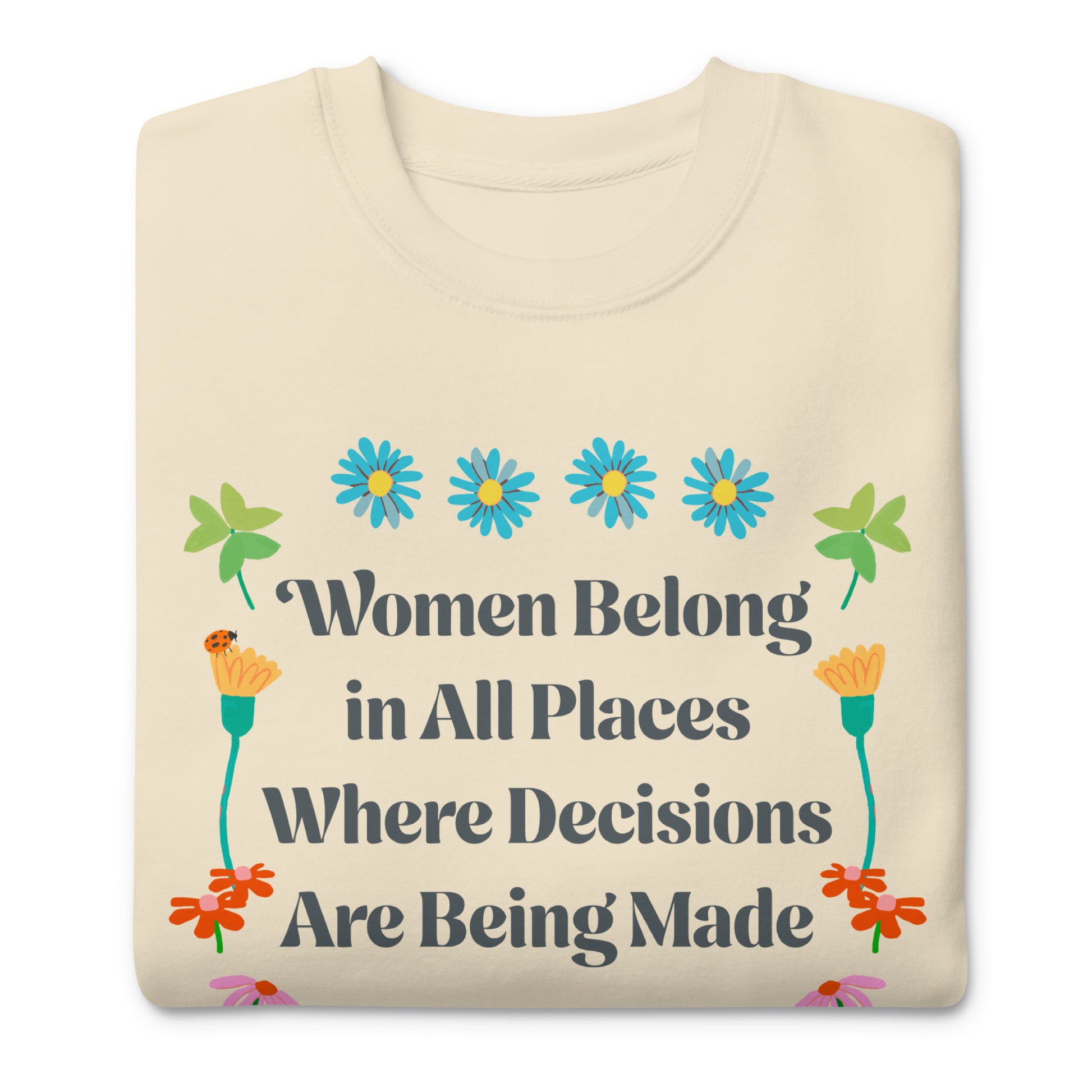 Folded cream sweatshirt displaying Ruth Bader Ginsburg feminist quote with colorful flower illustrations and “Women Belong in All Places” typography.