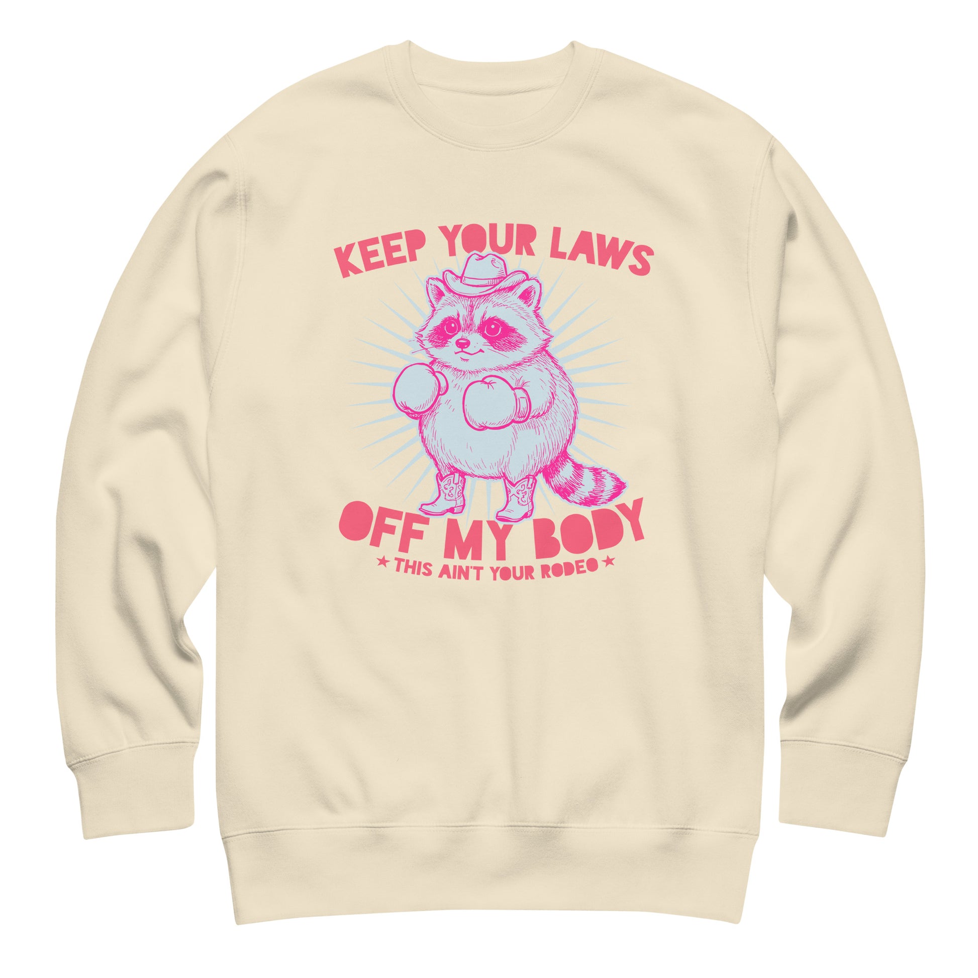 Cream unisex premium sweatshirt with pink raccoon graphic and “Keep Your Laws Off My Body” wording in clean activist style.