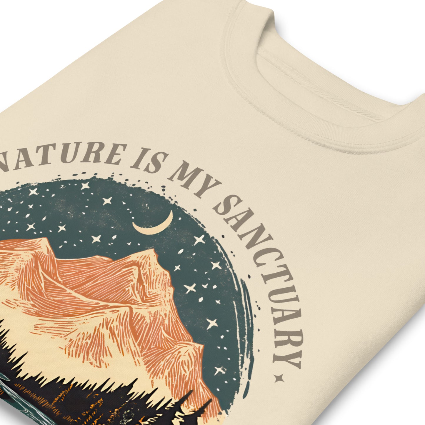 Close-up cream sweatshirt print showing scenic mountain artwork with pine trees, river, and “The Earth Is My Temple” phrase in outdoor design.