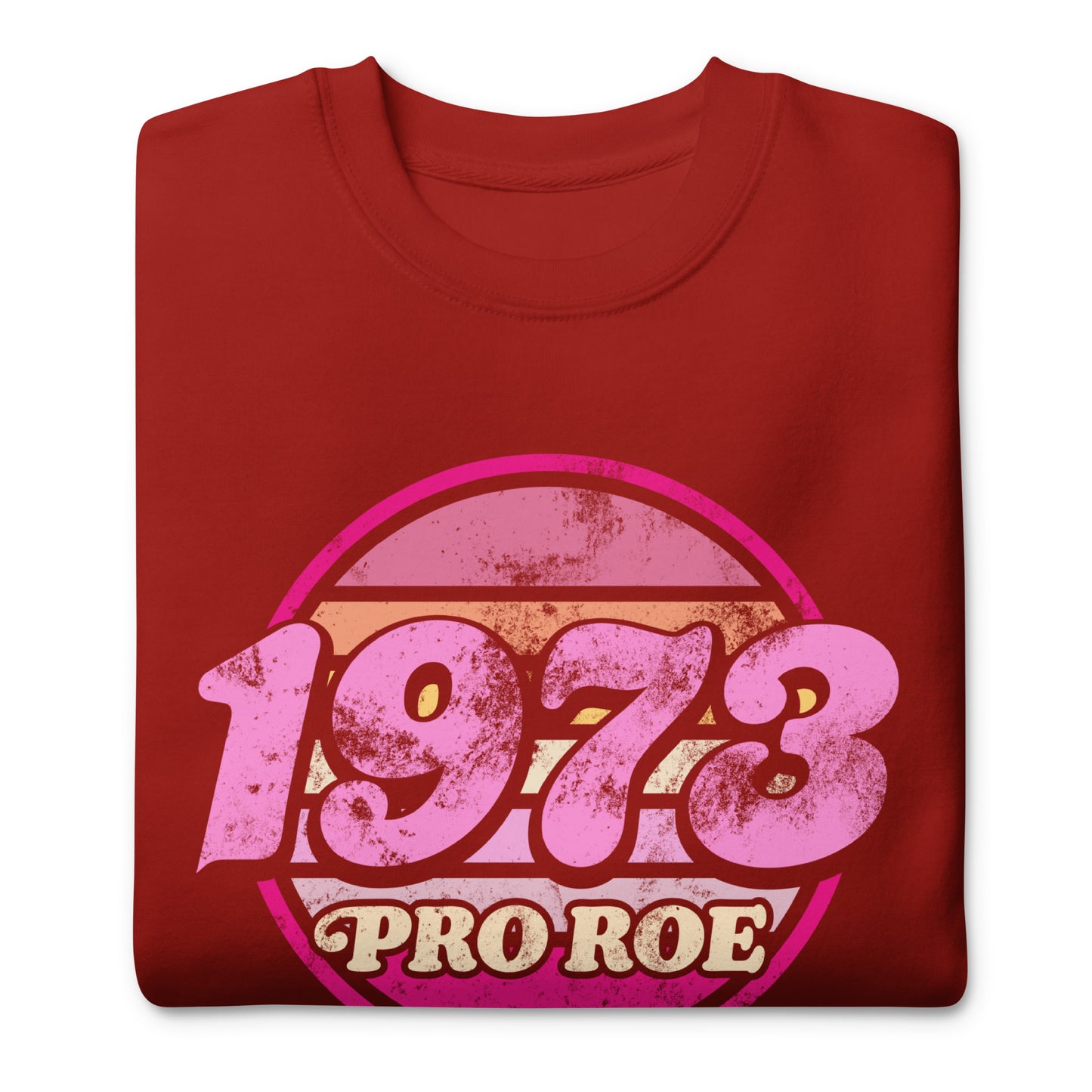 Folded cardinal red unisex premium sweatshirt showing a distressed circular badge reading “1973 PRO ROE,” retro typography and worn texture visible on soft fleece fabric.