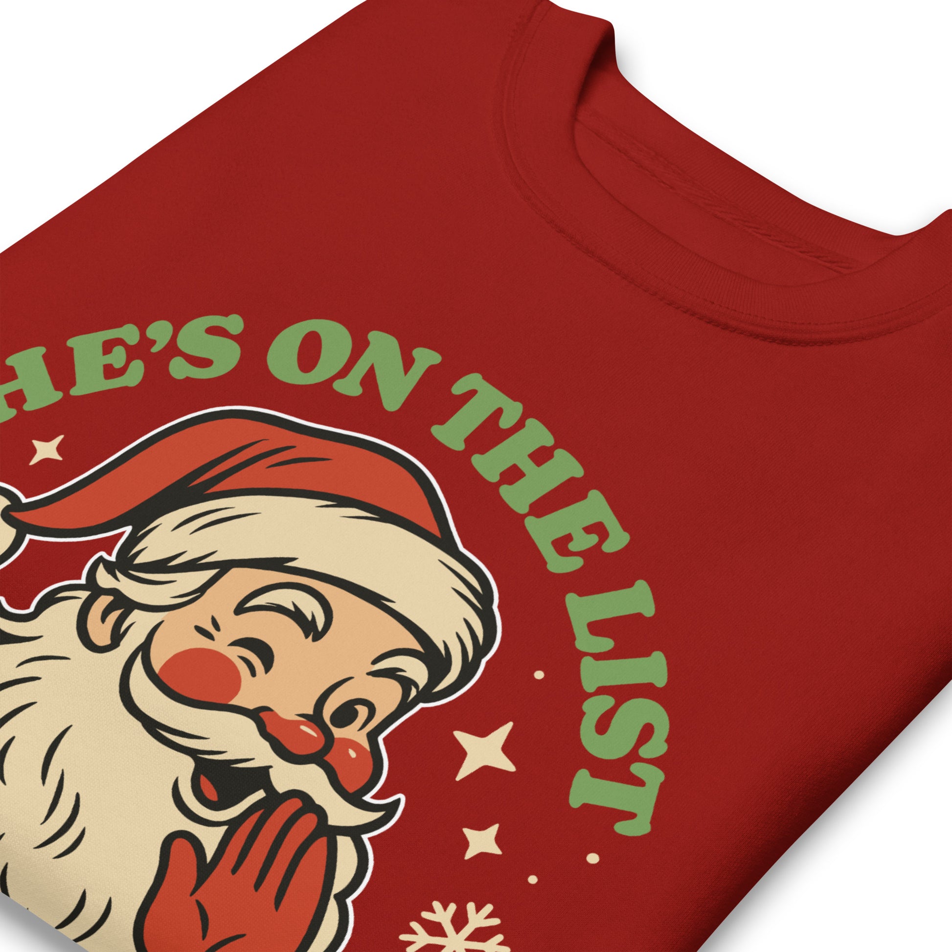 Close-up view of the retro Santa artwork and “He’s On the List” lettering on a red sweatshirt, highlighting the warm vintage tones.