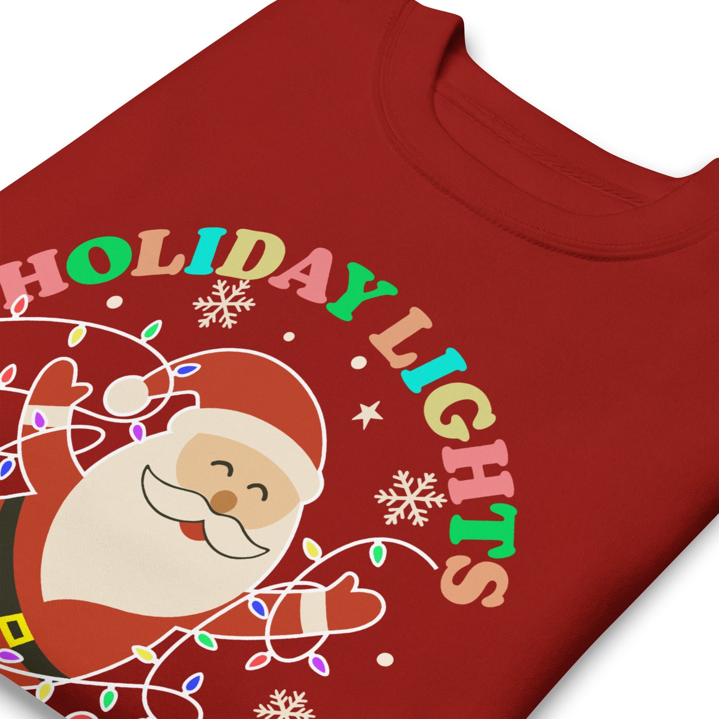 A close-up of a red unisex sweatshirt showing Santa surrounded by bright holiday lights, stars, and snowflakes with the printed message “HOLIDAY LIGHTS ABOLISH ICE,” offered by Blue Wave USA.
