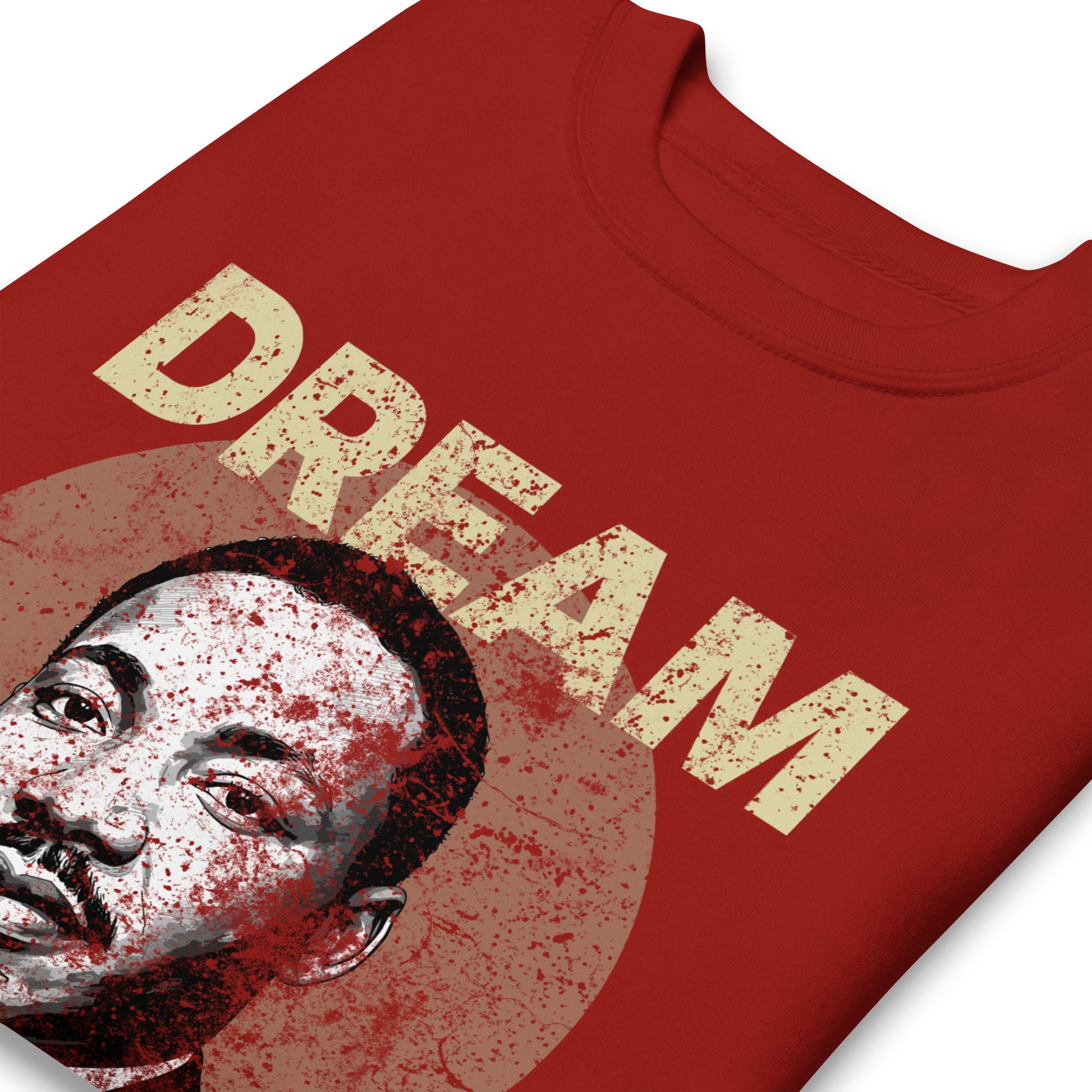 Close-up of a red unisex premium sweatshirt displaying the worn “DREAM LIKE KING” text with MLK’s portrait inside a distressed circle. Vintage activist graphic from Blue Wave USA.