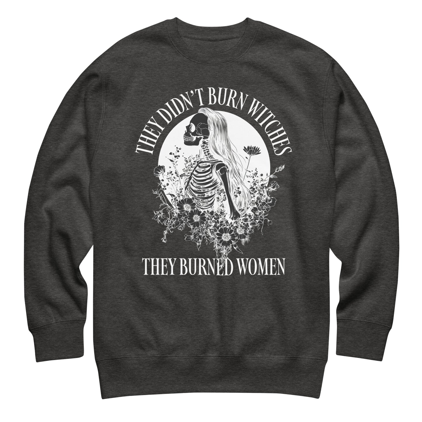 Charcoal heather unisex premium sweatshirt laid flat featuring gothic skeleton illustration with floral accents, centered circular layout, printed message “THEY DIDN’T BURN WITCHES THEY BURNED WOMEN.”